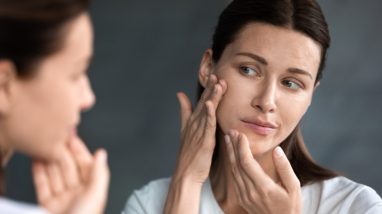 Young woman examining her skin in a mirror