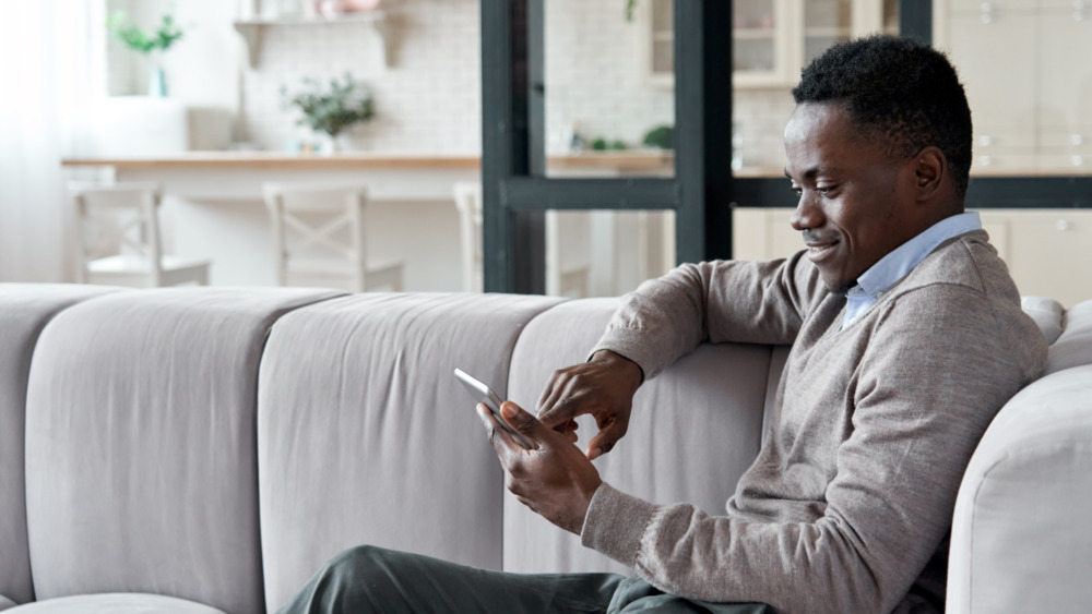 Man sitting on couch and smiling at tablet