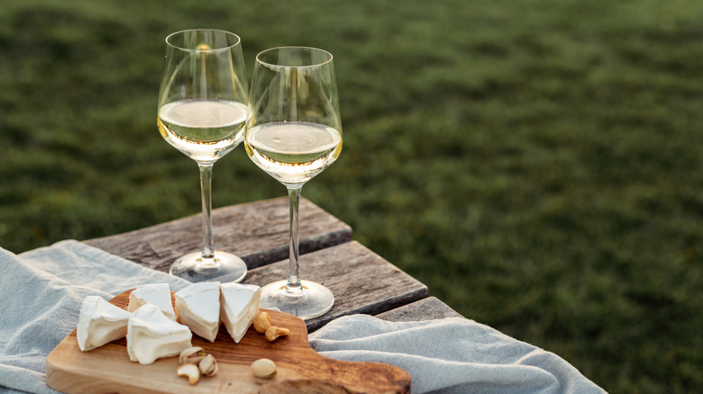 Two glasses of white wine on a wooden table beside grass 