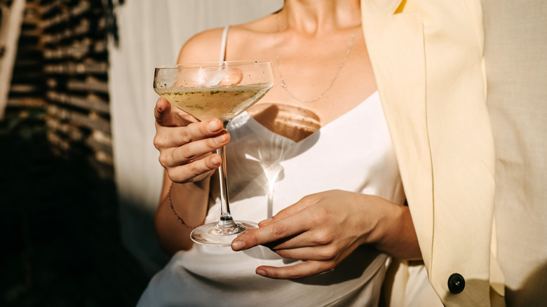 Woman wearing a silk slip dress holding a glass of champagne