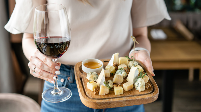 Woman holding a cheese plate and a glass of red wine