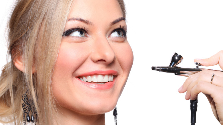 Blond woman getting airbrush makeup