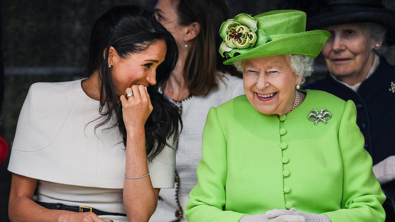 Queen Elizabeth II sitting and smiling with Meghan Markle