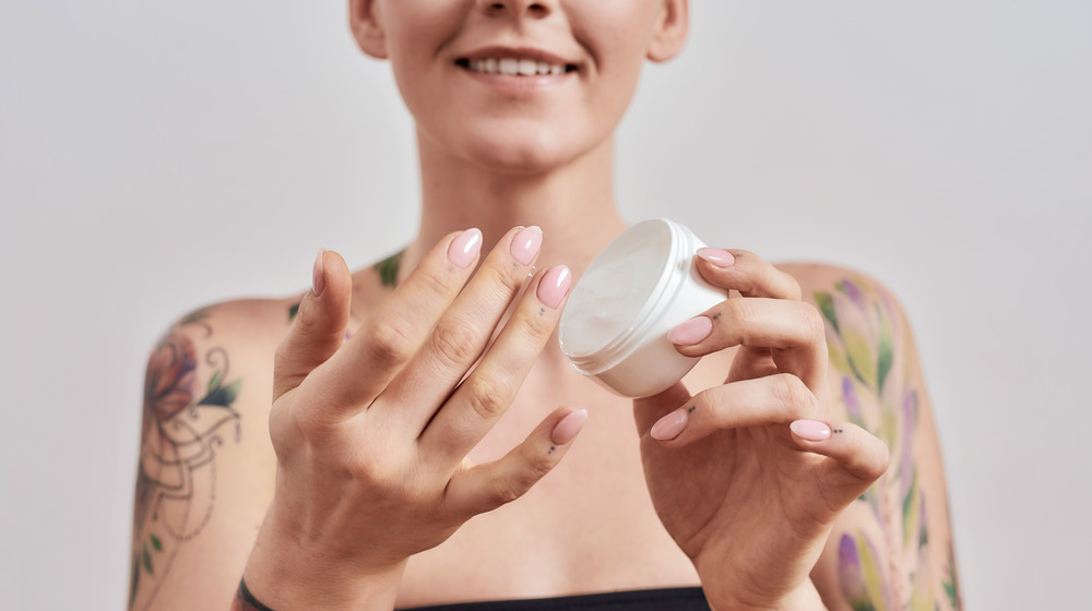 Tattooed woman applying lotion