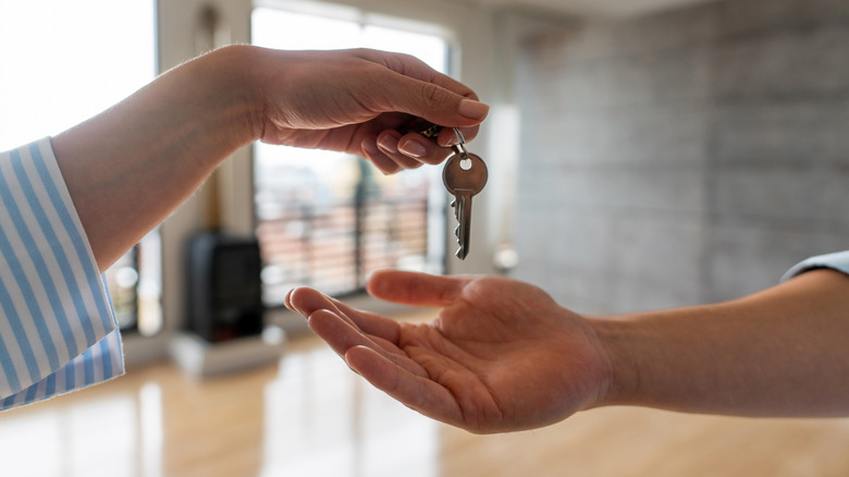 Person handing off house keys to someone else 