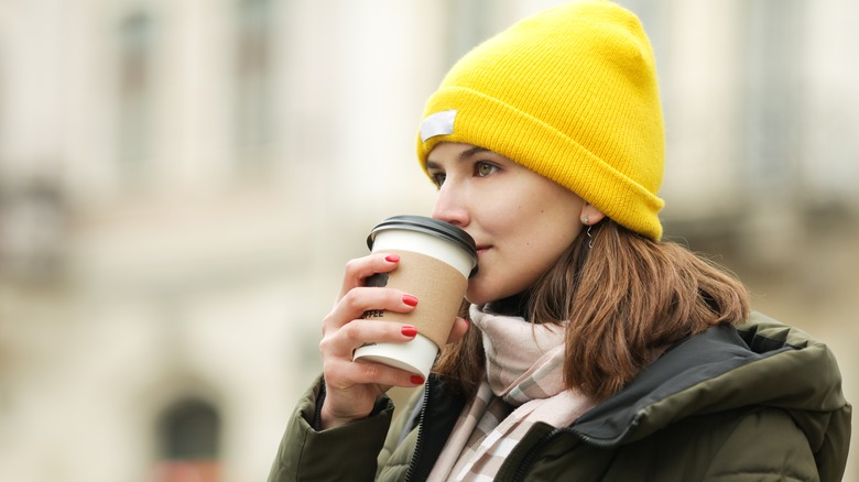 A yellow beanie on woman drinking coffee