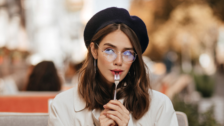 woman wearing beret and using fork