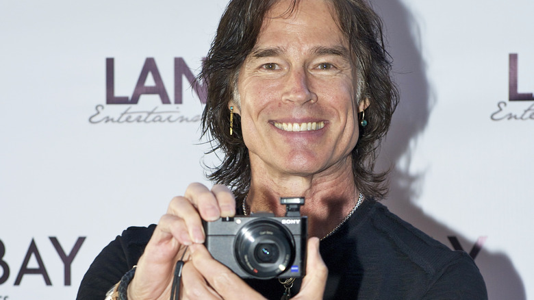 Ron Moss holding a camera and smiling