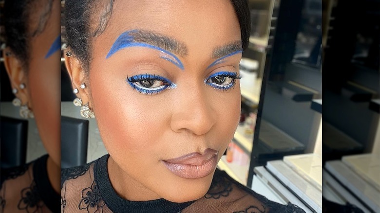 Woman with blue liner and color fill on eyebrows 