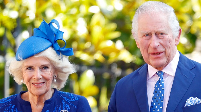 Queen Camilla and King Charles III smiling, both wearing blue