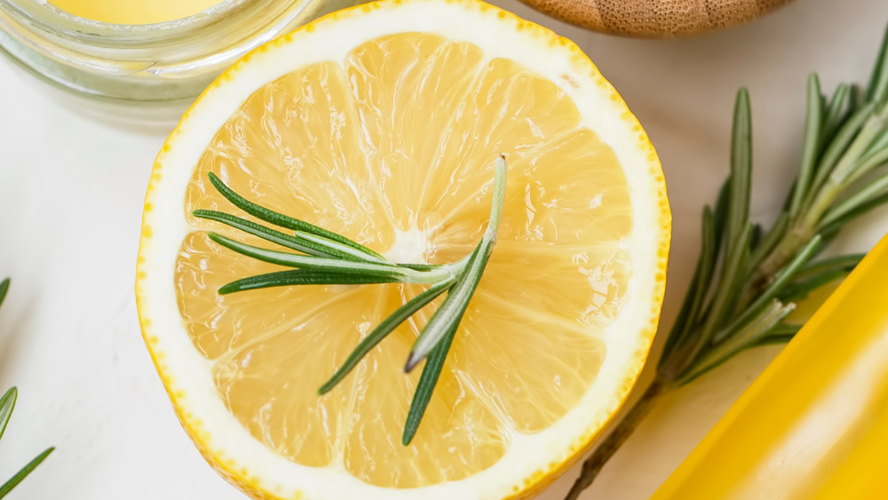 Sprigs of rosemary on top of and near a fresh cut lemon half