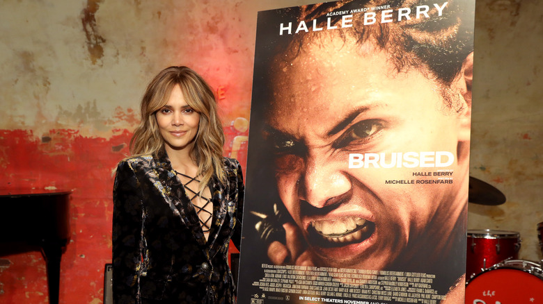 halle berry posing next to "Bruised" poster