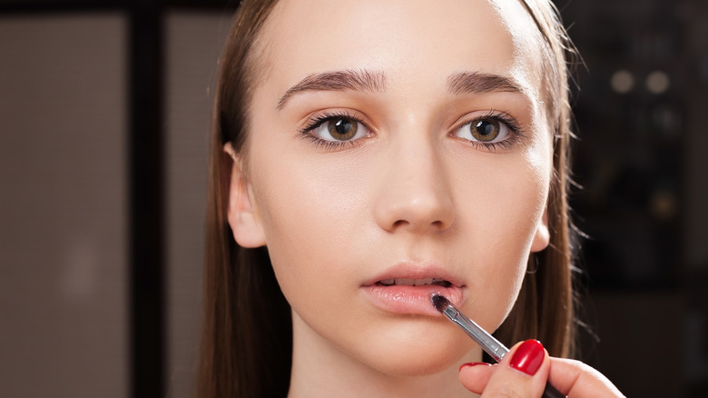 Woman applying primer to lips