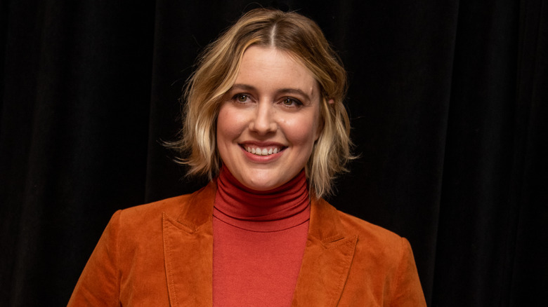 Greta Gerwig in orange jumper and coat