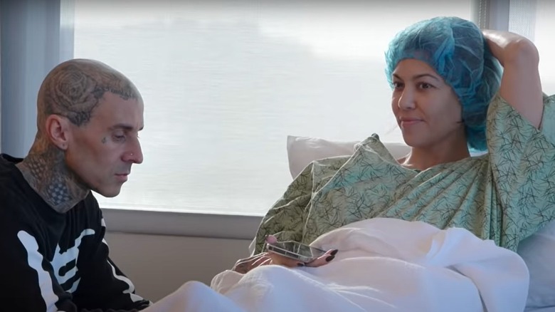 Kourtney Kardashian in hospital bed, and Travis Barker next to her