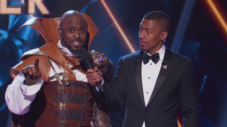 Nick Cannon holding a microphone to Wayne Brady