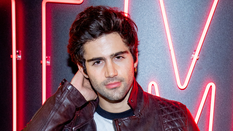 Max Ehrich posing with red neon lights