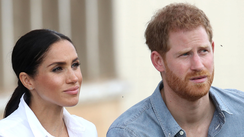 Meghan Markle listening closely and Prince Harry with furrowed brow