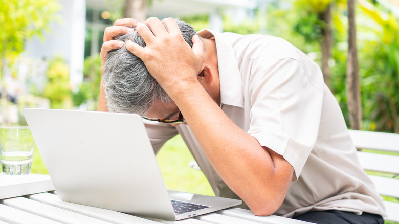 Older man using laptop outside