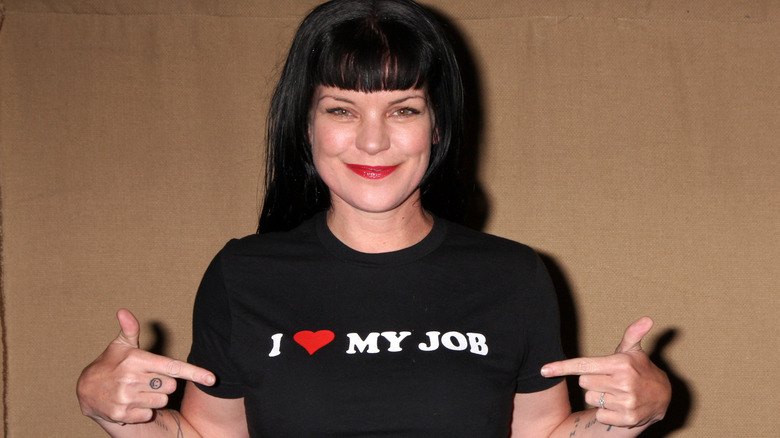 Pauley Perrette smiling and pointing to her shirt 