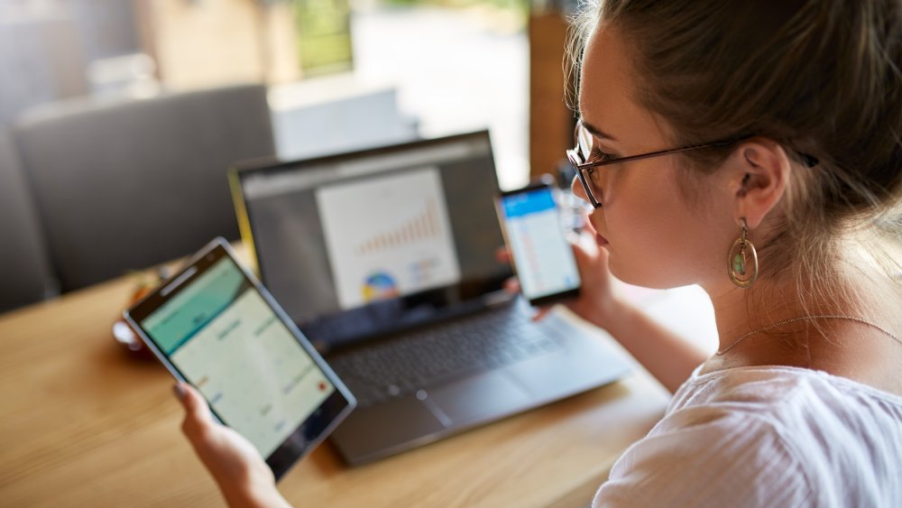 Woman using 2 cell phones and a laptop