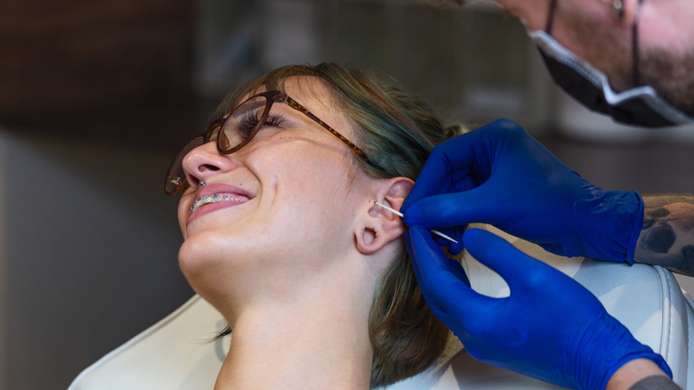 woman getting ear pierced