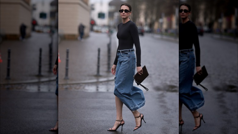 A woman wearing a bodysuit and denim maxi skirt