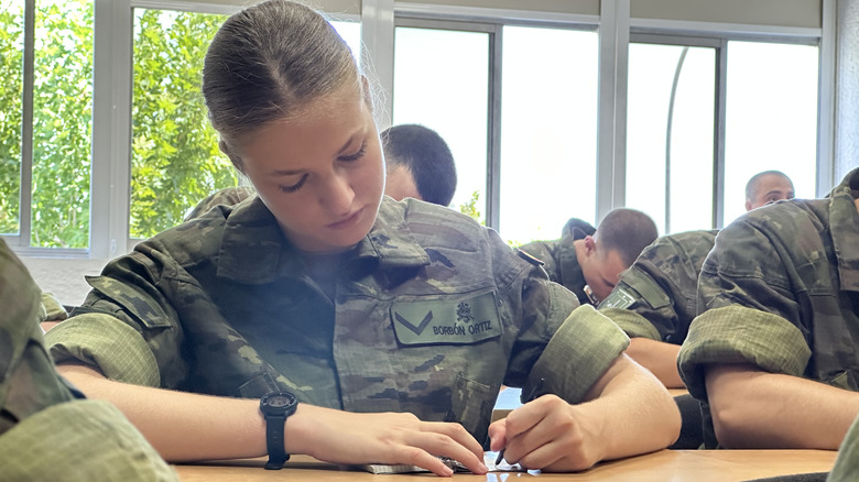 Princess Leonor in green military fatigues sitting in classroom and writing