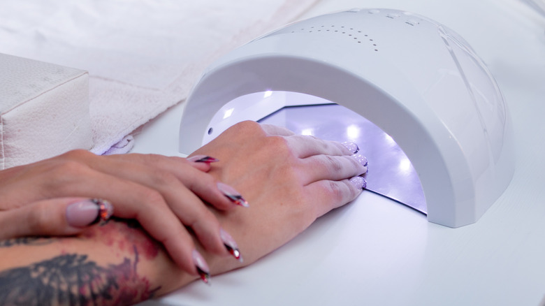 Woman drying nails under ultraviolet LED 