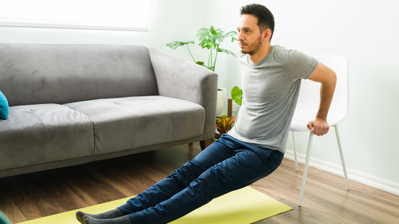 person doing tricep dips with chair during home workout