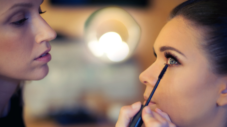 Makeup artist applies mascara.