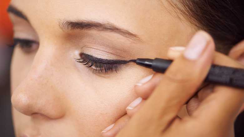 woman applying liquid eyeliner wing