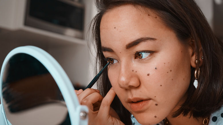 woman applying liquid eyeliner 