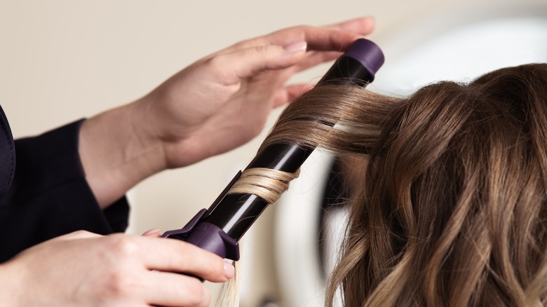 Hairstylist curling someone's hair