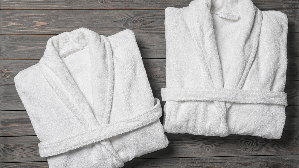 Two white bathrobes folded on a wooden table 