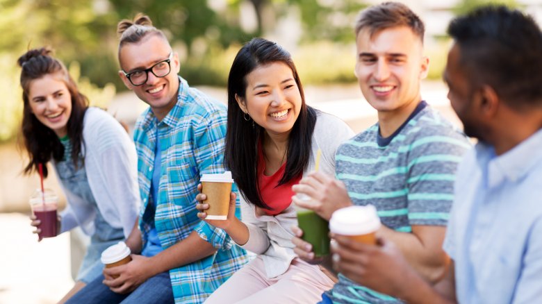 Group of young adults in conversation drinking smoothies and coffee