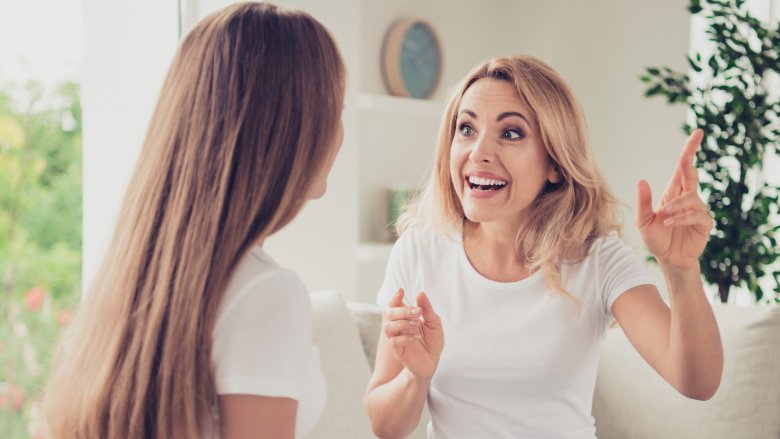 Women wearing white T-shirts chatting enthusiastically on a couch