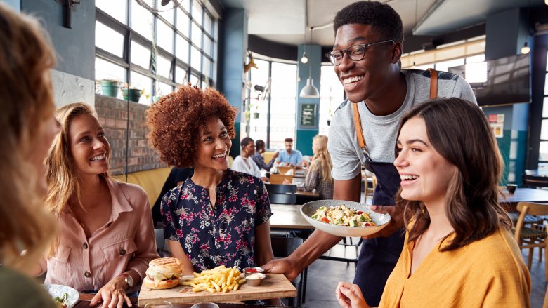 Women dining and chatting with charming server