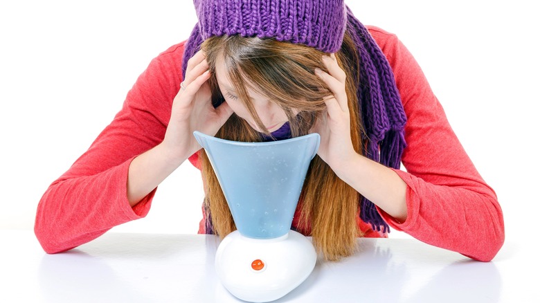 Woman using diffuser to breathe in essential oils