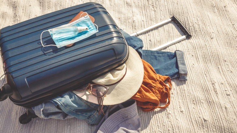 suitcase with clothes hand sanitizer and mask