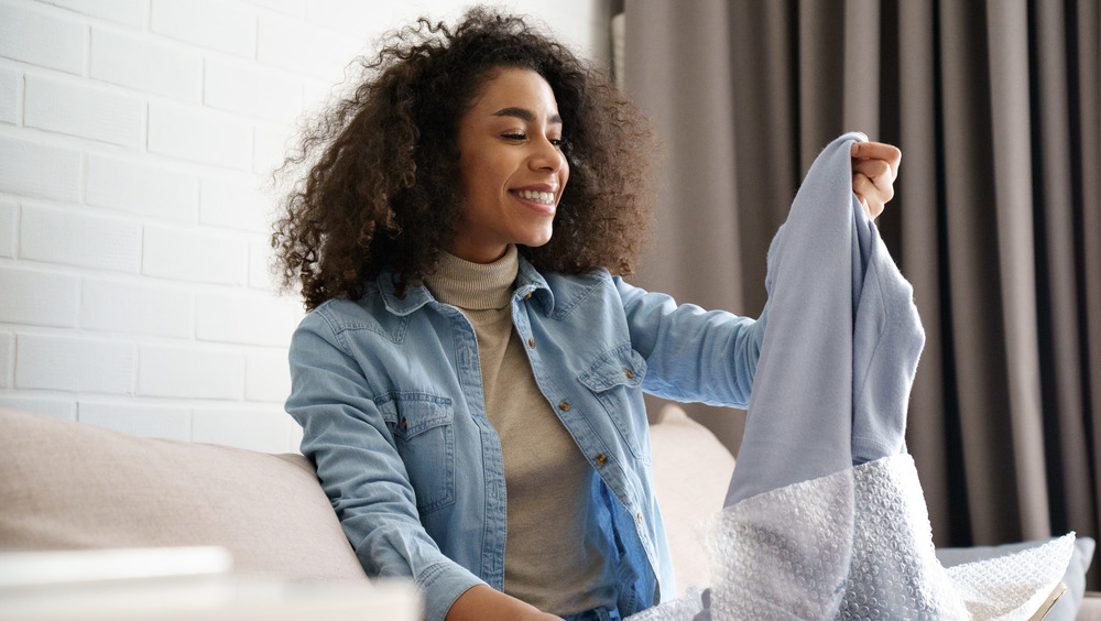 Woman opening up package filled with clothing she has purchased