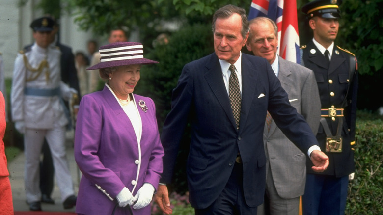 Queen Elizabeth and George HW Bush smiling and walking