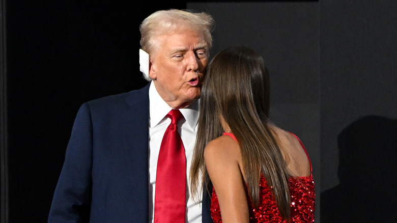 Donald Trump leaning over to kiss his granddaughter Kai Trump