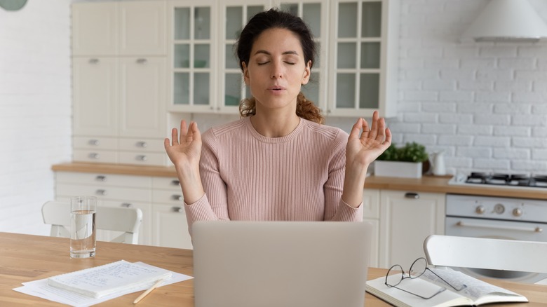 Woman practices breathing and meditation at her desk