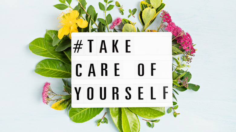 Light board reads "#take care of yourself" with flowers behind it