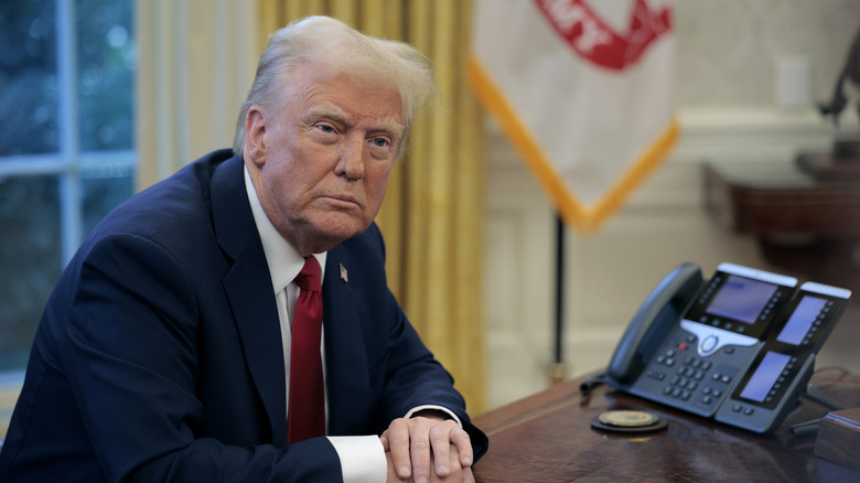 Donald Trump sits at a desk