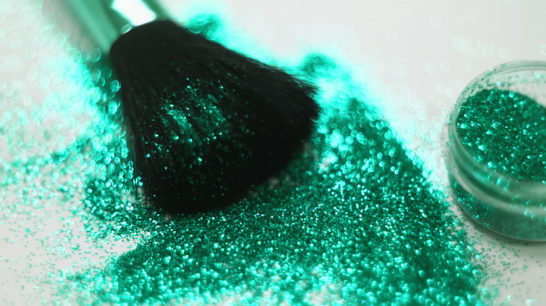 A makeup brush and spilled green glitter