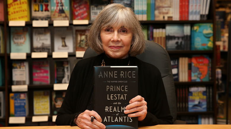 Anne Rice smiling and holding a book