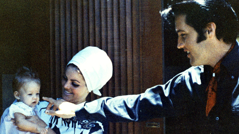 Priscilla Presley holding baby Lisa Marie as Elvis Presley points