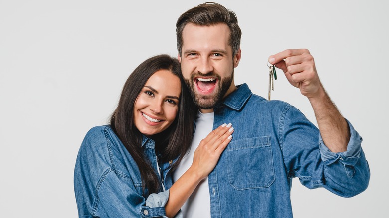 A couple holding up keys to their new home